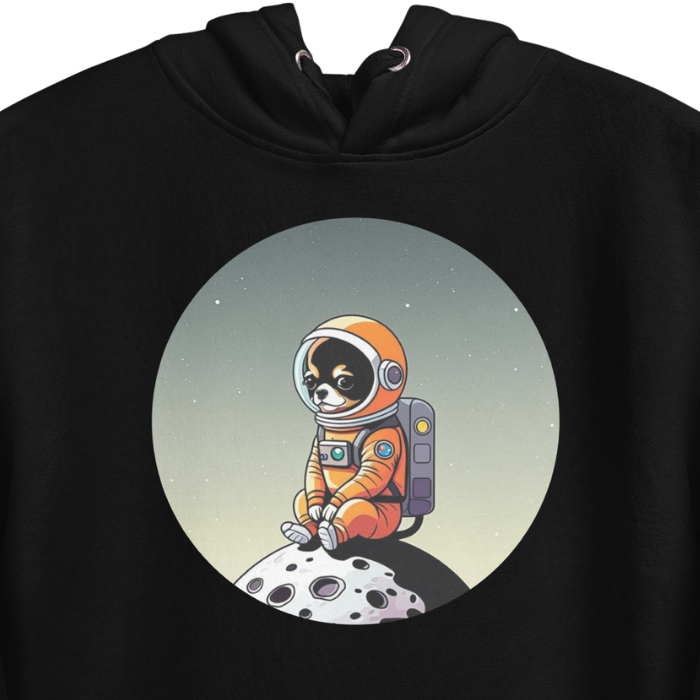 Close up photo of a black color hoodie with a cute illustration printed on the chest of a Chihuahua dog wearing an astronaut suit siting in a little moon.