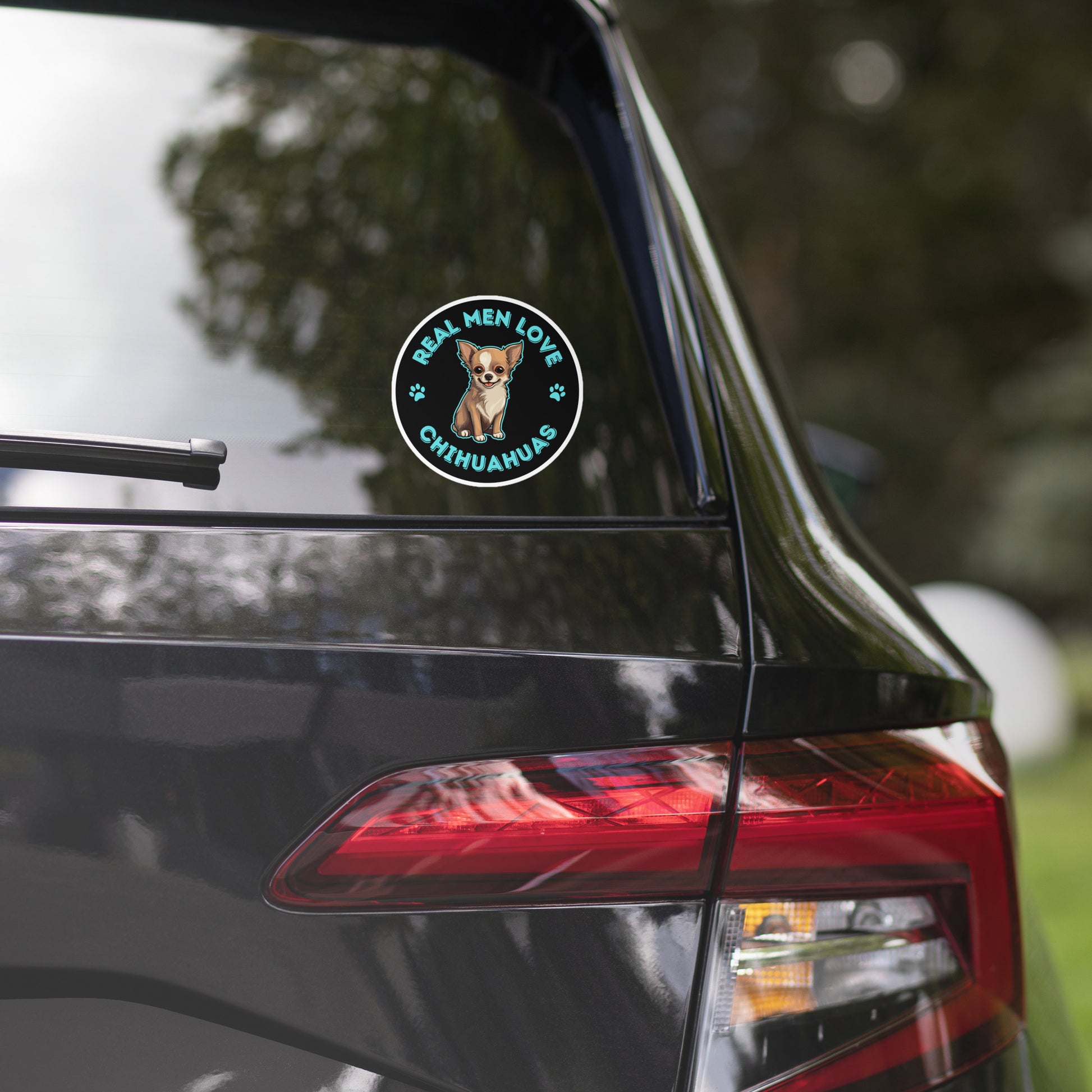 Image of the back window of a car with a 4 x 4 inches black round sticker with a cute illustration of a Chihuahua Dog and the words "Real Men Love Chihuahuas" around it.