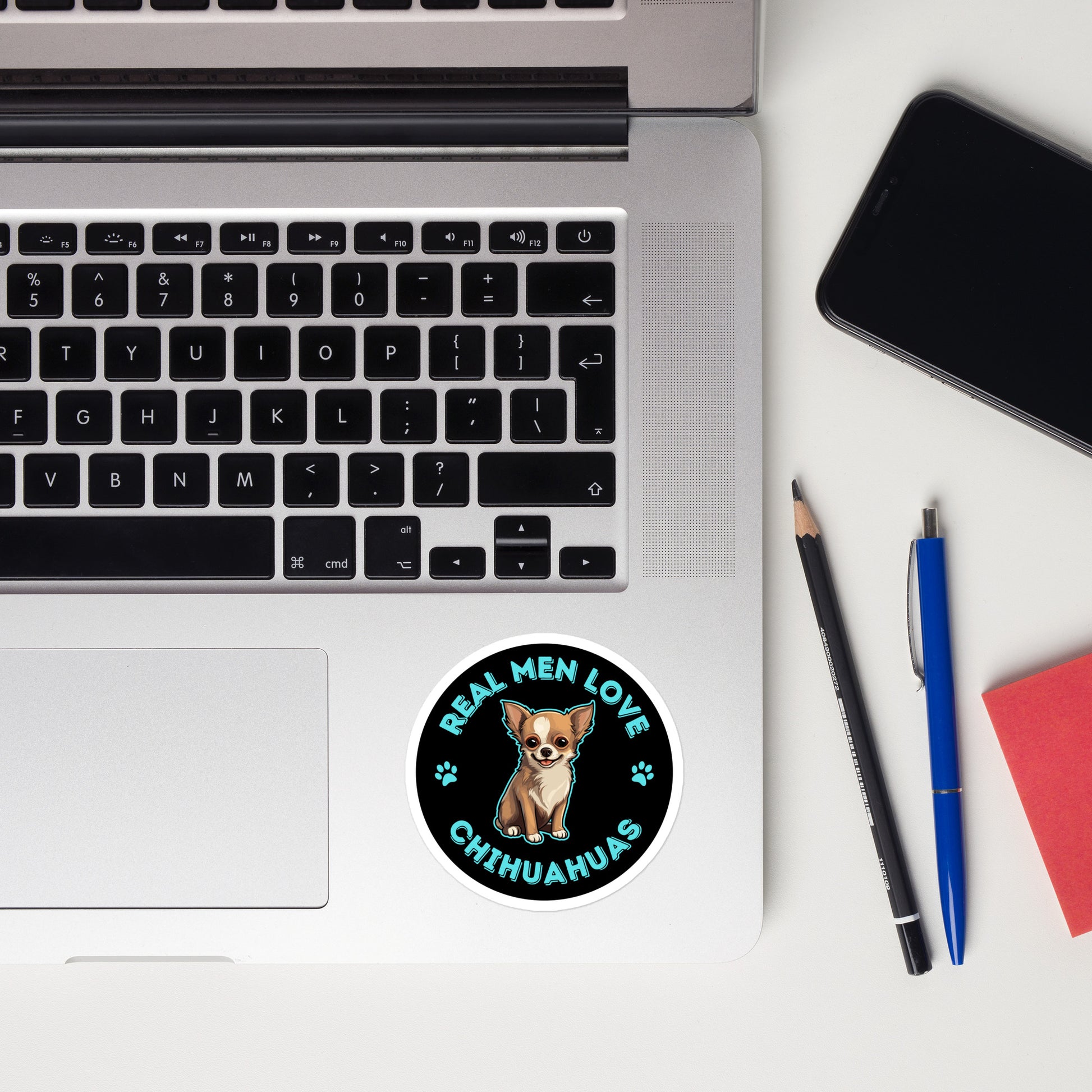 Image of laptop keyboard with a 3 x 3 inches black round sticker with a cute illustration of a Chihuahua Dog and the words "Real Men Love Chihuahuas" around it.