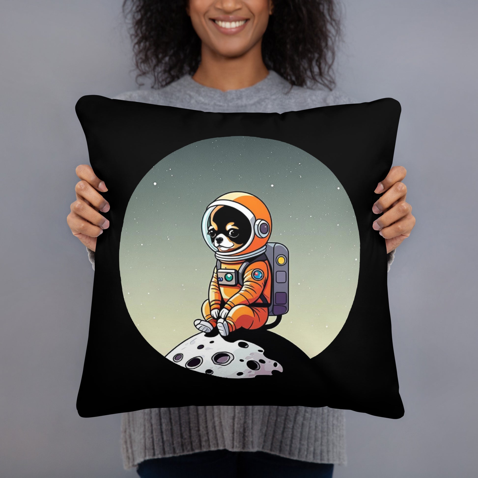 Photo of a young woman presenting to the camera a black color 18x18 inches throw pillow with a cute illustration of a  Chihuahua dog wearing an astronaut suit, sitting on a small moon.