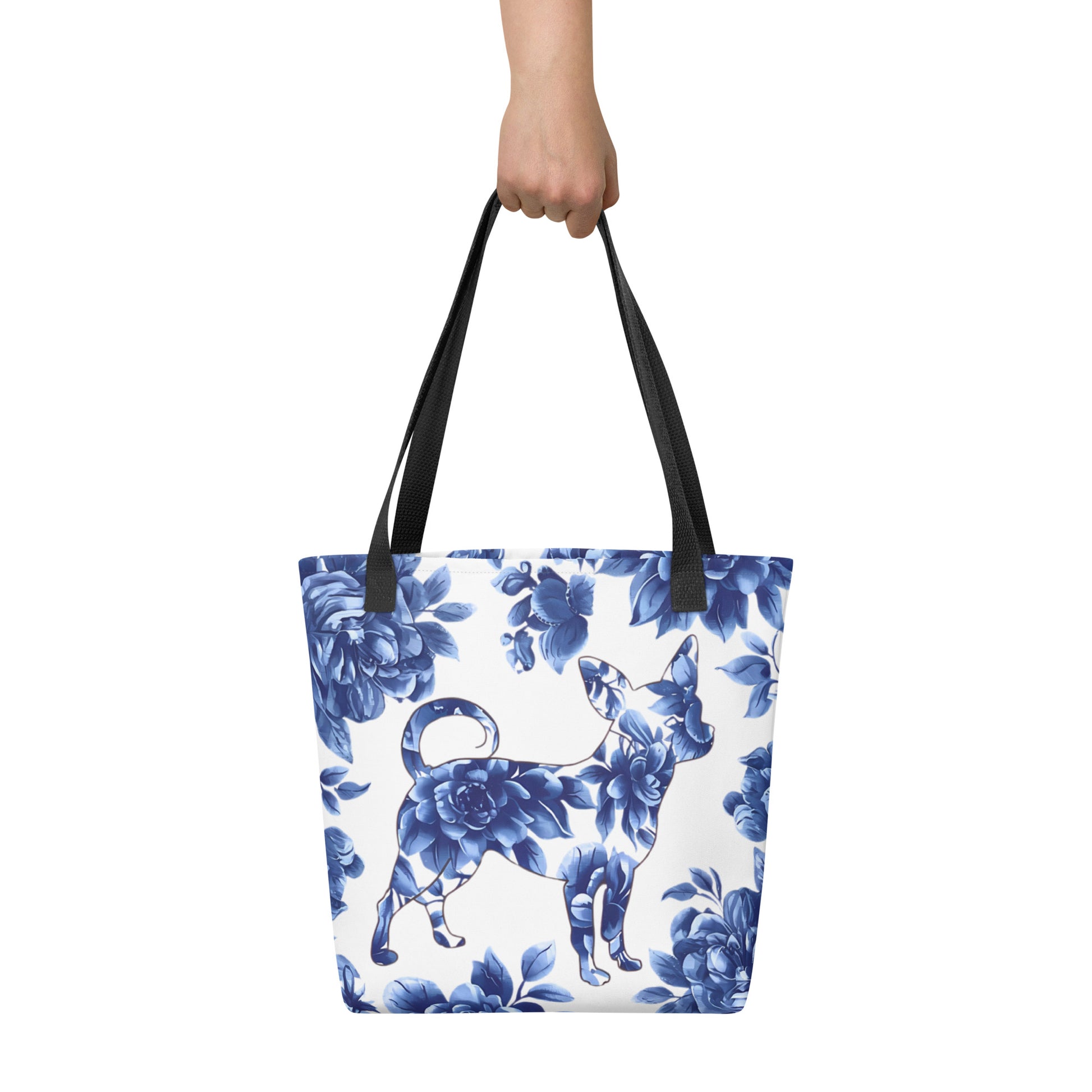 Photo of a woman's hand holding a white 15x15 inches tote bag with an all over print with a silhouette of a Chihuahua filled with blue floral background