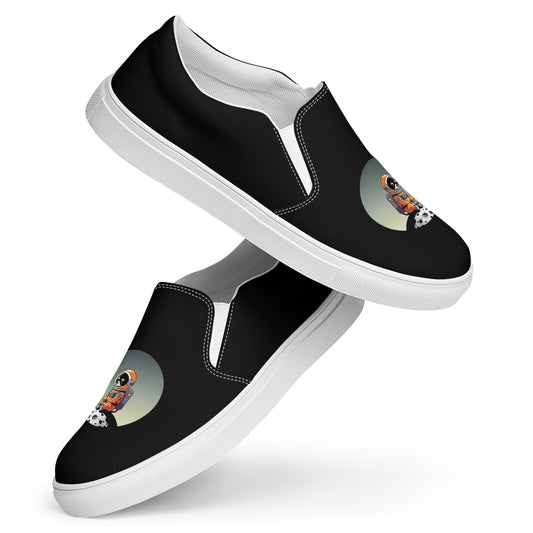 Product image of a black pair of women's slip on canvas shoes featuring a cute astronaut Chihuahua dog sitting on a small moon.